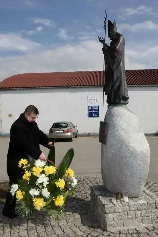 Kwiaty pod pomnikiem i tablicą Jana Pawła II